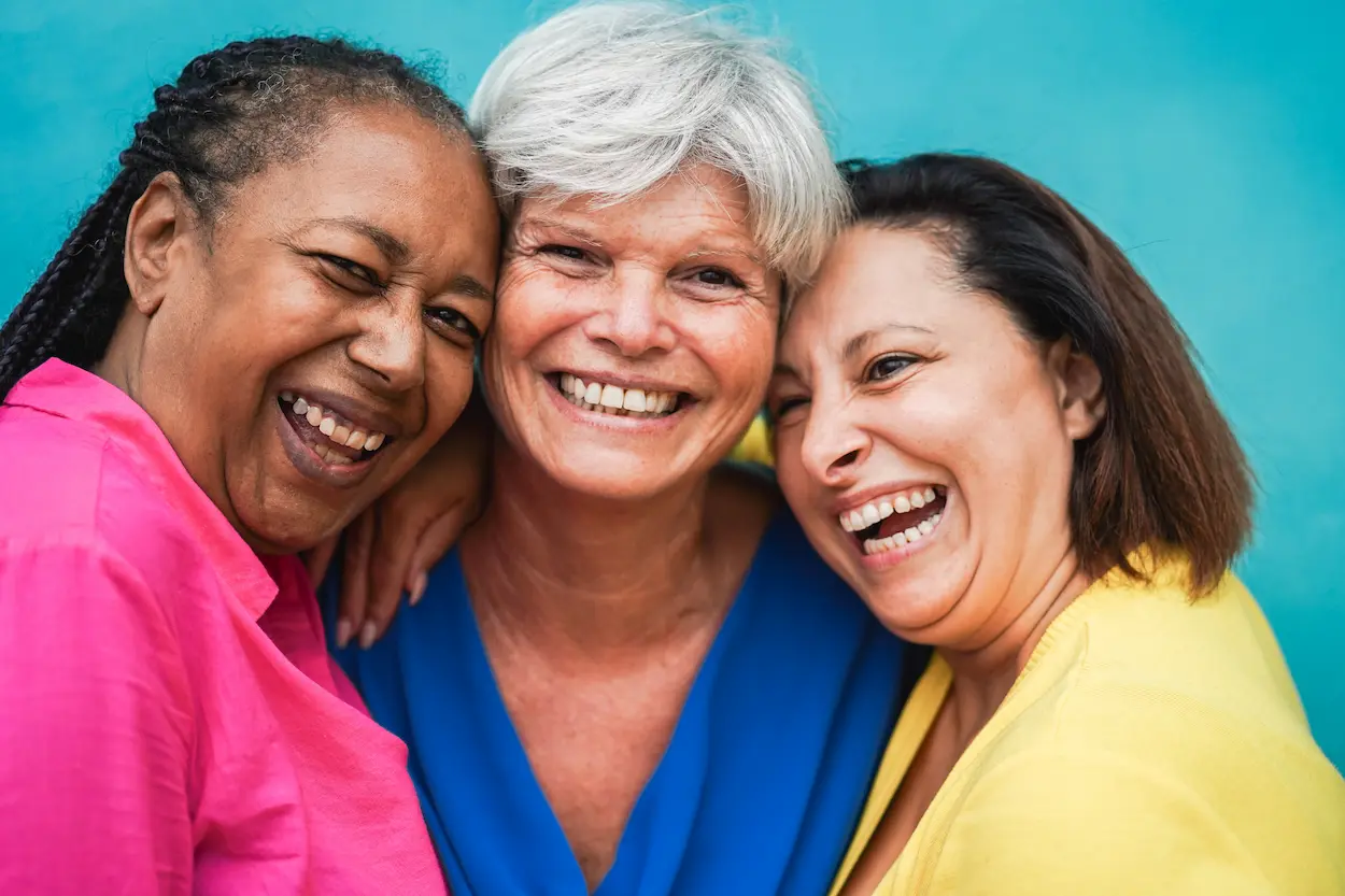 Three Smiling Women in Pink, Blue, and Yellow